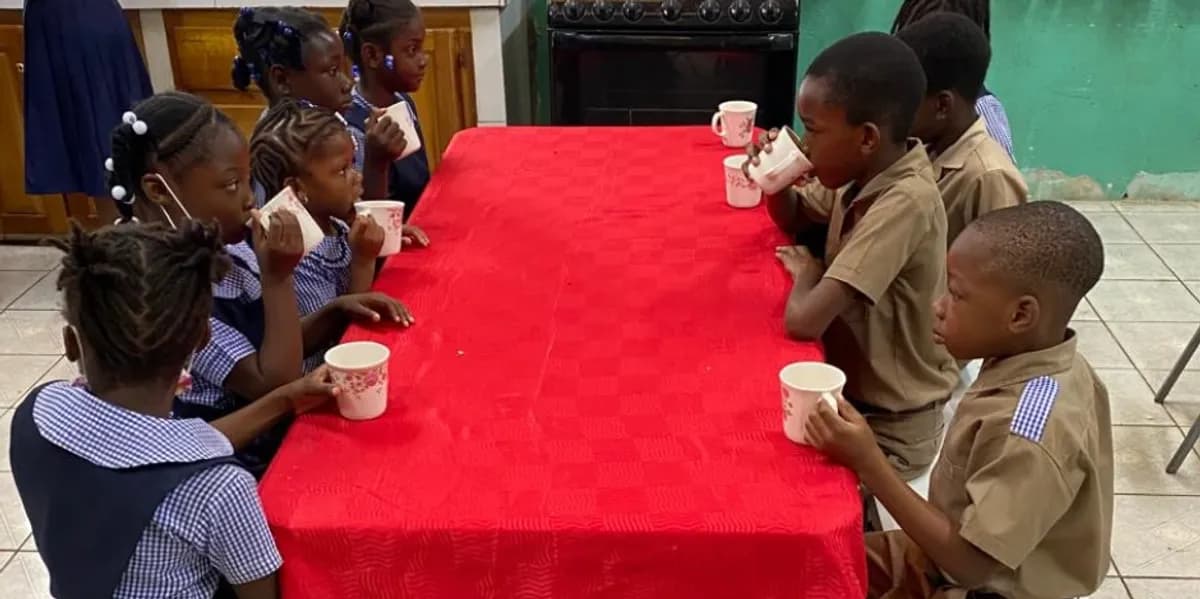 Children in school uniforms enjoying breakfast together at a table with red tablecloth