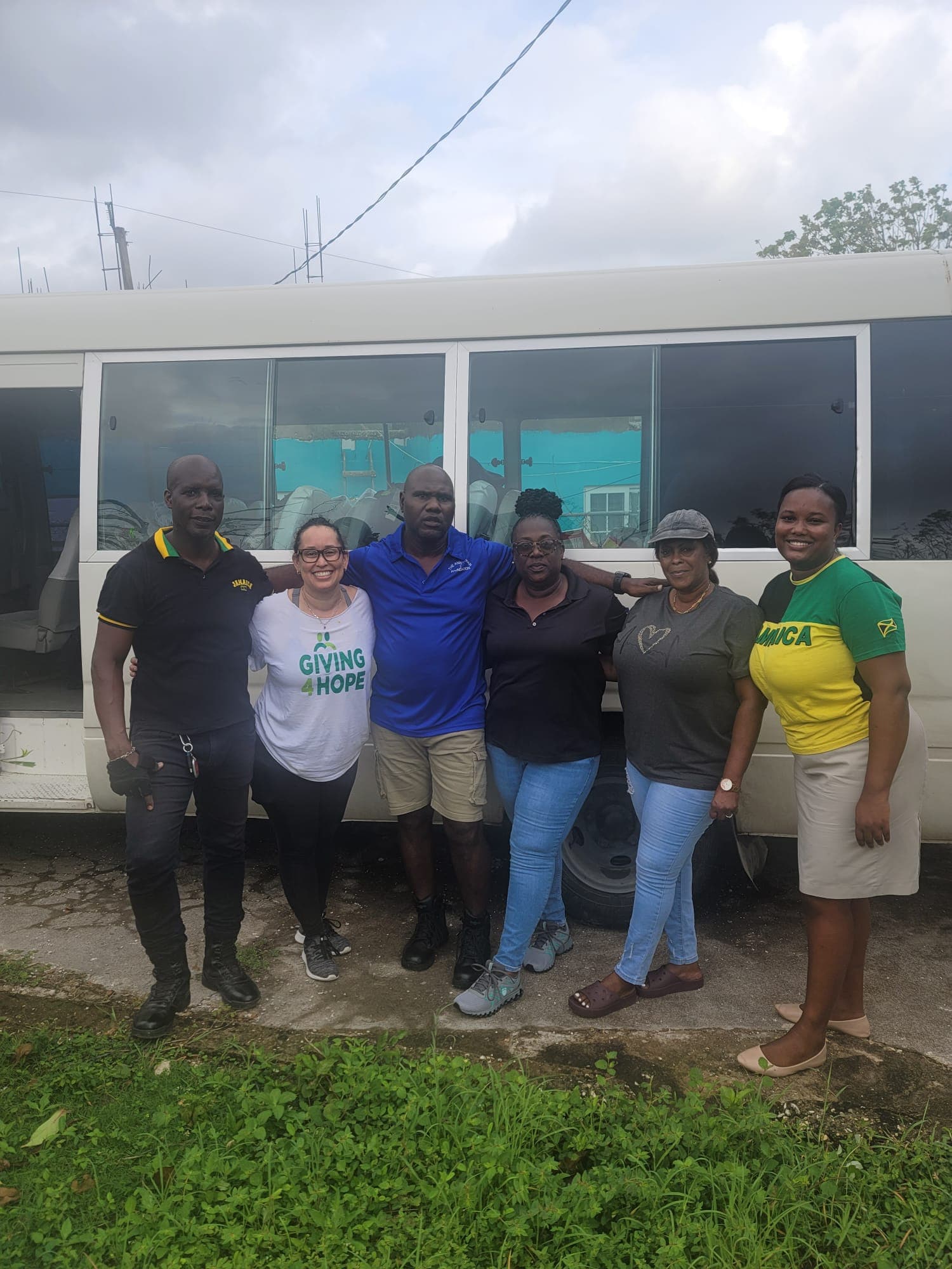 Team portrait of the foundation and Giving 4 Hope relief crew in front of the Jamaica Tours bus